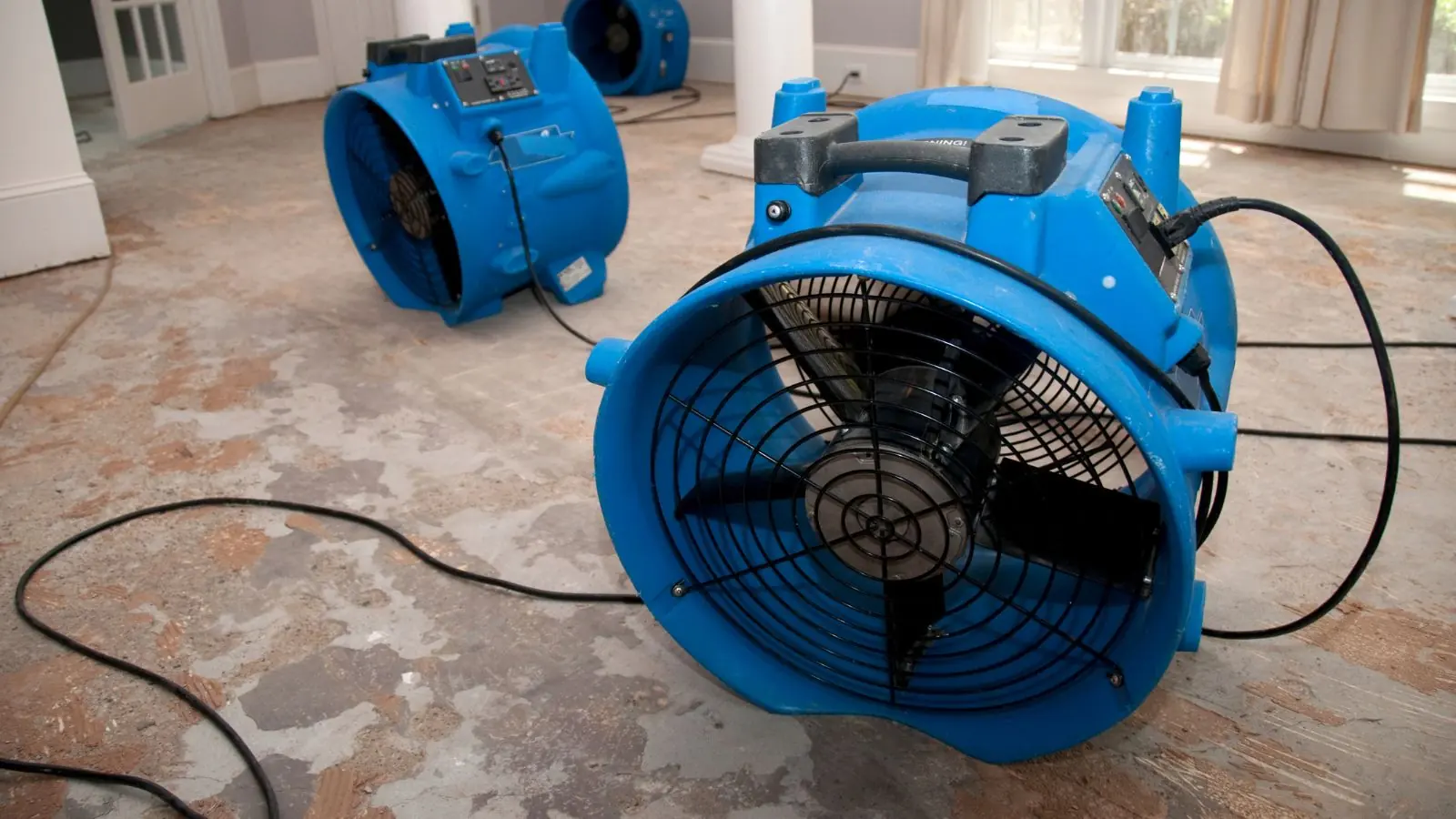 Blue air mover running on a floor during structural drying